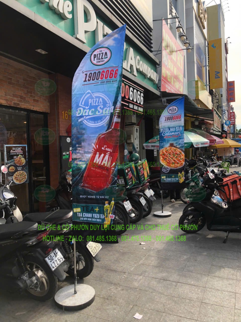 Cờ cánh buồm có hình pizza và thông điệp quảng cáo được dựng bằng đế tròn trước The Pizza Company.