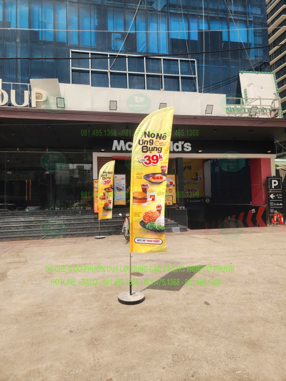 Cờ cánh buồm nền vàng có hình sản phẩm và thông điệp quảng cáo, đặt trước mặt tiền McDonald’s.