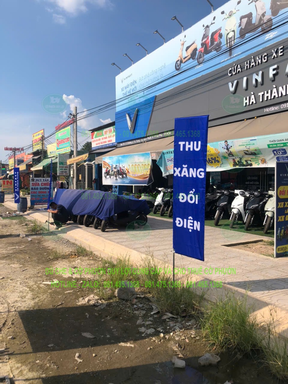 Cờ chữ nhật nền xanh có nội dung “Thu xăng đổi điện” trước cửa hàng xe VinFast Hà Thành.