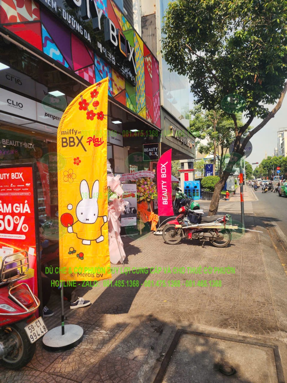 Cờ nền vàng có hình minh họa và chữ nổi bật, đặt sát mặt tiền cửa hàng.