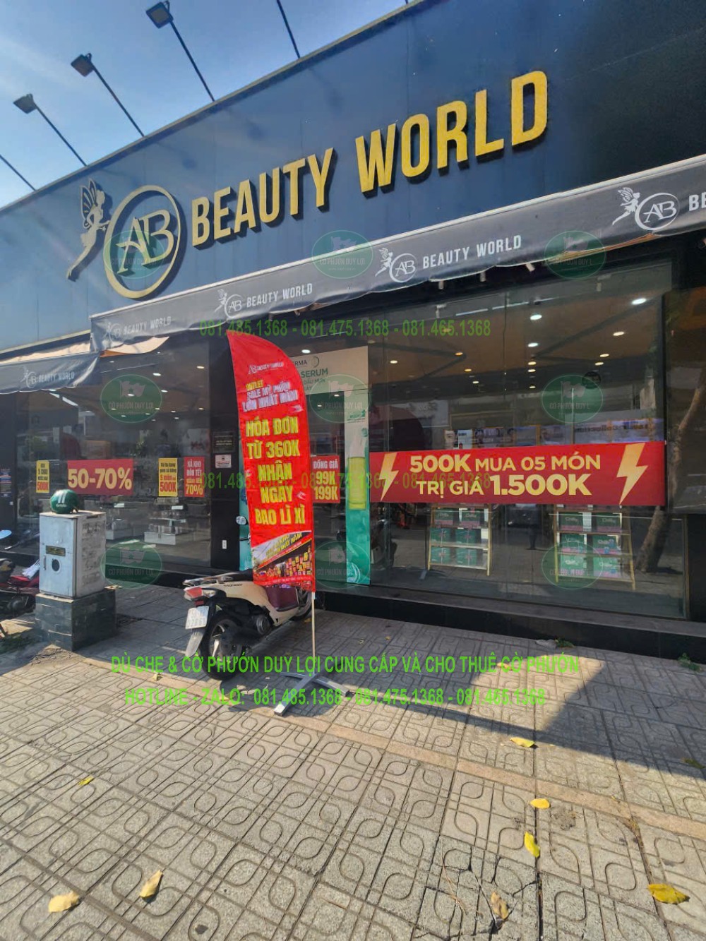 Cờ khuyến mãi được bố trí trước showroom BEAUTY WORLD, cùng bảng hiệu và băng rôn mặt tiền.