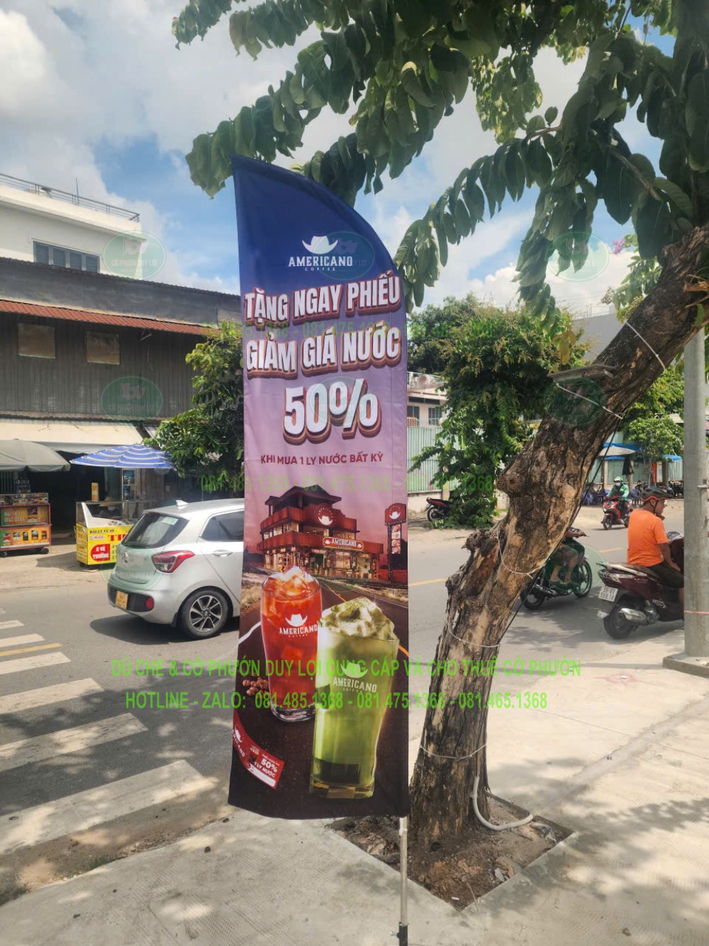 Góc chụp rõ lá cờ cạnh cây xanh, thể hiện dòng điều kiện của chương trình và hình ly nước.
