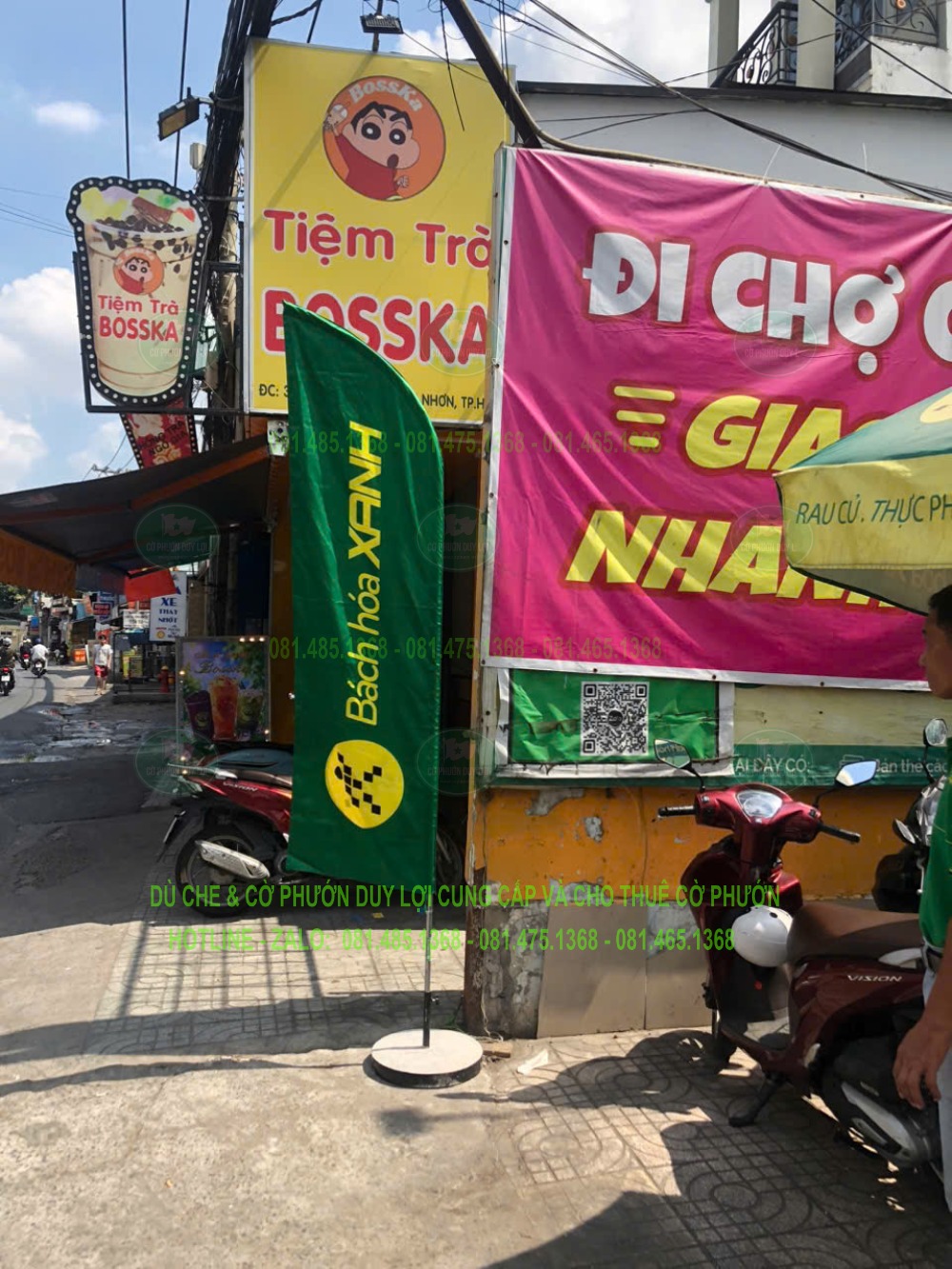 Cờ Bách Hóa Xanh dựng gần băng rôn và các bảng khác, minh họa cách nhận diện bằng hai màu chủ đạo.