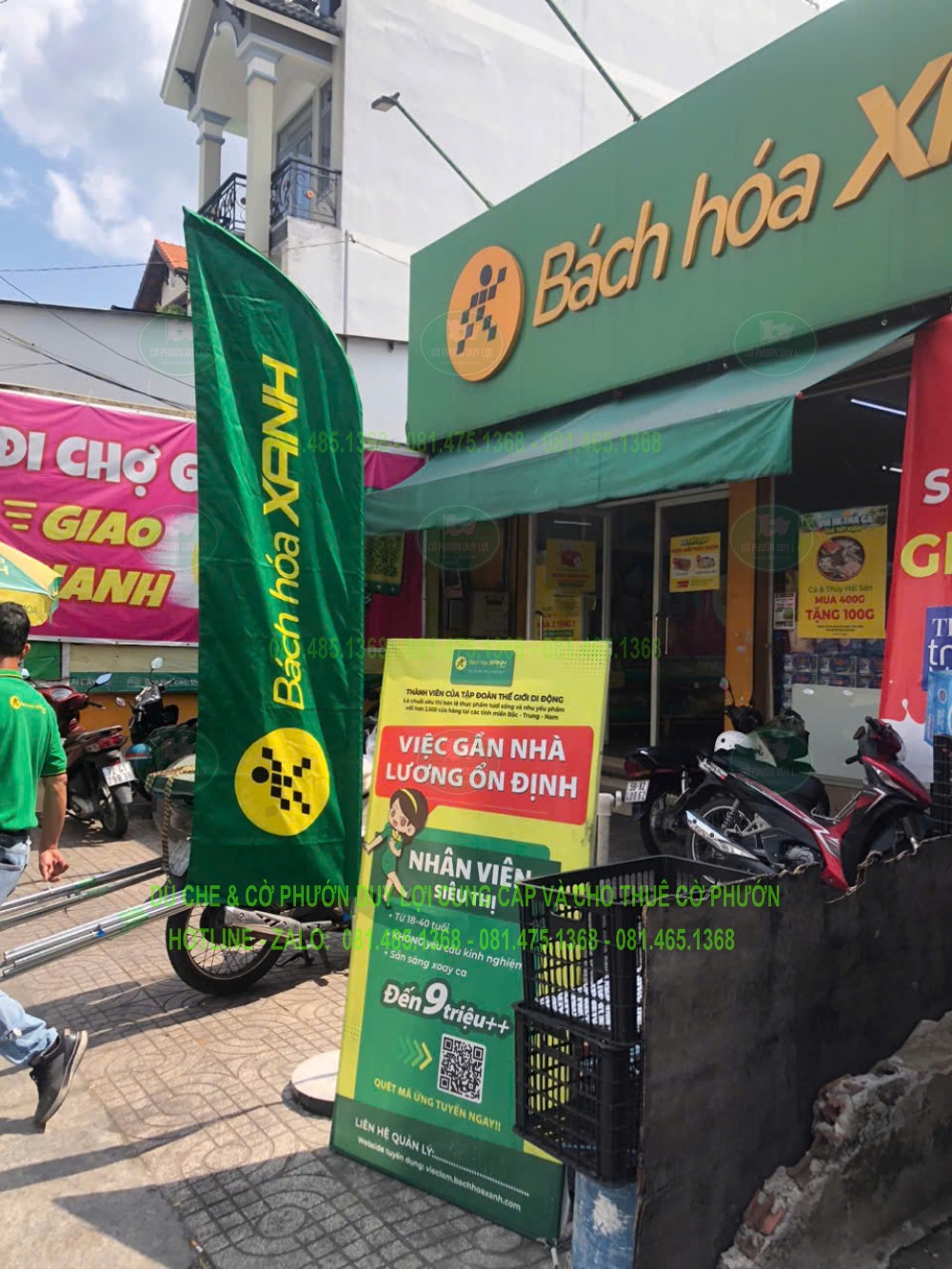 Cờ Bách Hóa Xanh đặt trước mặt tiền cùng bảng tuyển dụng và khu vực xe đỗ tại thời điểm chụp.