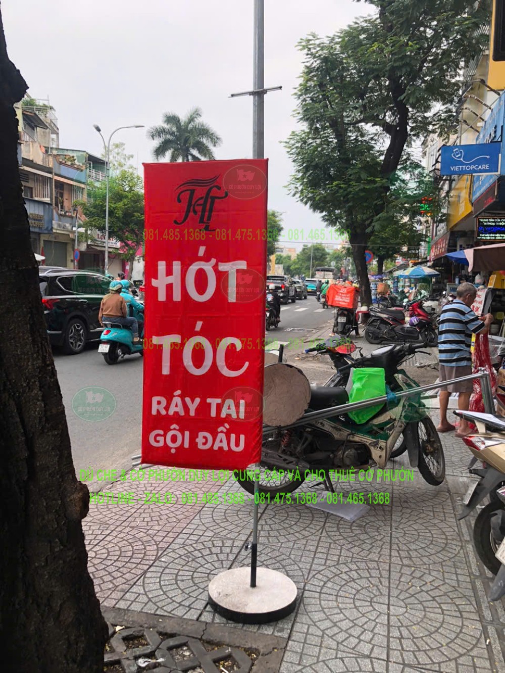 Cờ chữ nhật màu đỏ hiển thị các dịch vụ hớt tóc, ráy tai và gội đầu bằng những khối chữ lớn.