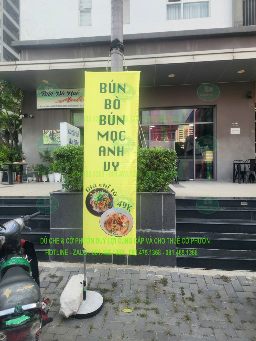 Cờ nền xanh vàng giới thiệu bún bò, bún mọc trước quán ăn, với tên món được xếp theo chiều dọc.