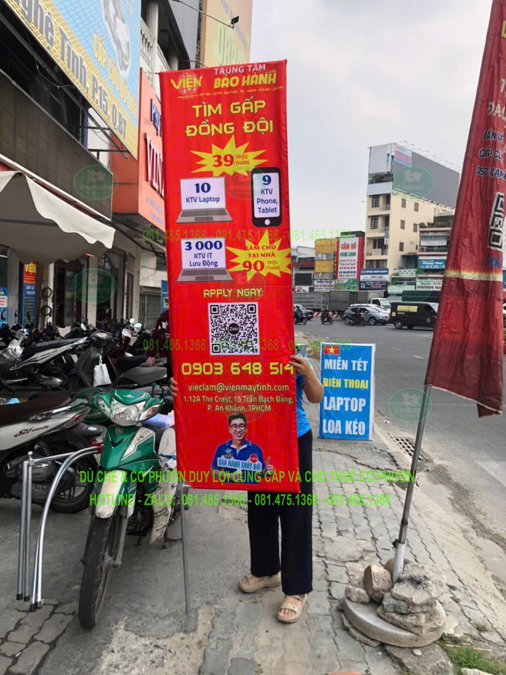 Cờ tuyển dụng nền đỏ đặt trước cơ sở, với các khối thông tin và hình bản đồ trên lá chữ nhật.