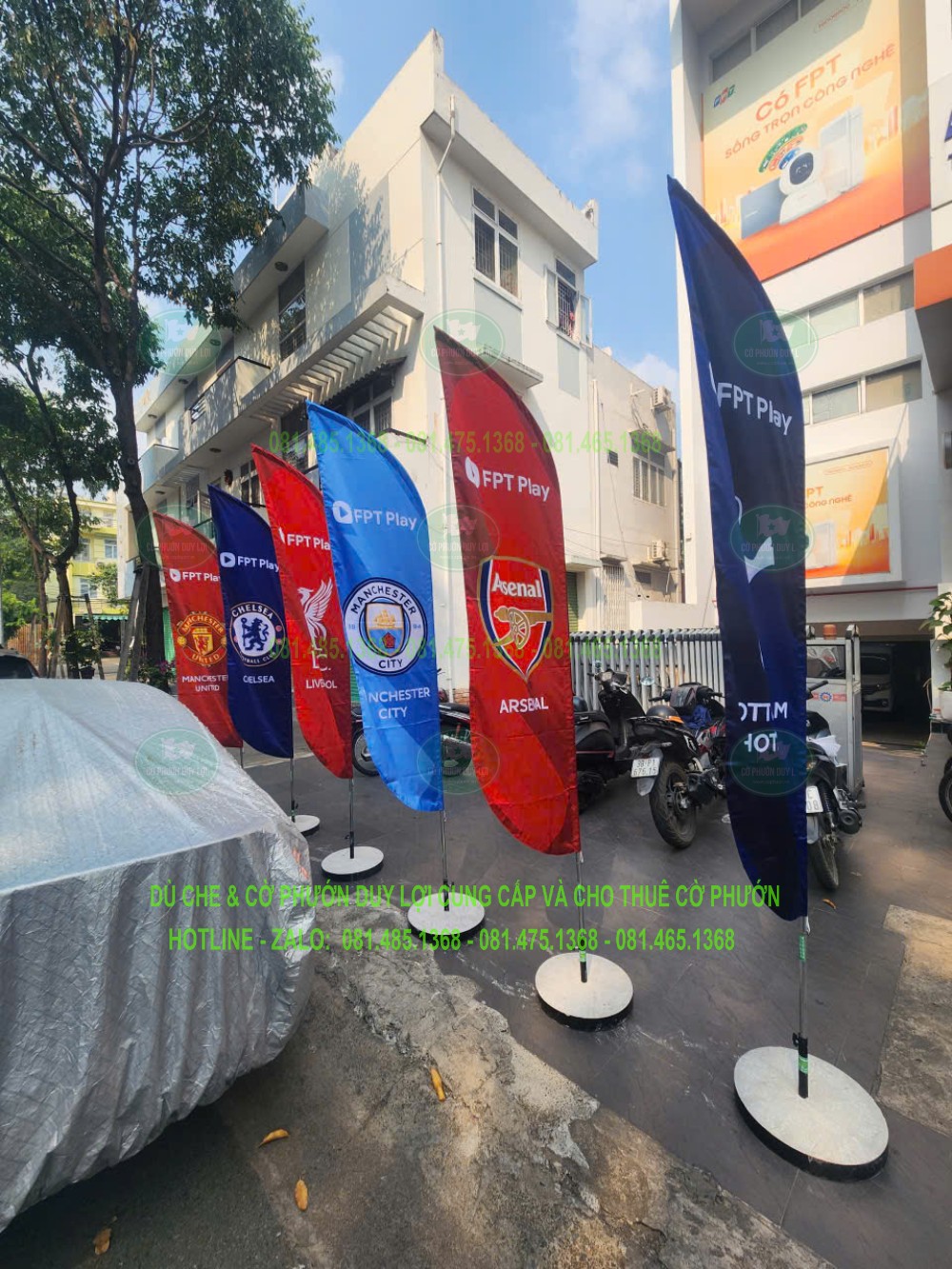 Các cờ FPT Play in nhận diện câu lạc bộ bóng đá được dựng trước mặt tiền bằng đế tròn.