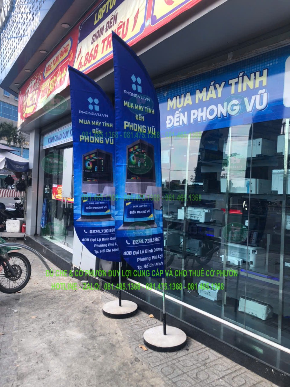 Hai cờ xanh Phong Vũ đặt trước mặt tiền kính, hiển thị thông điệp về máy tính và sản phẩm.