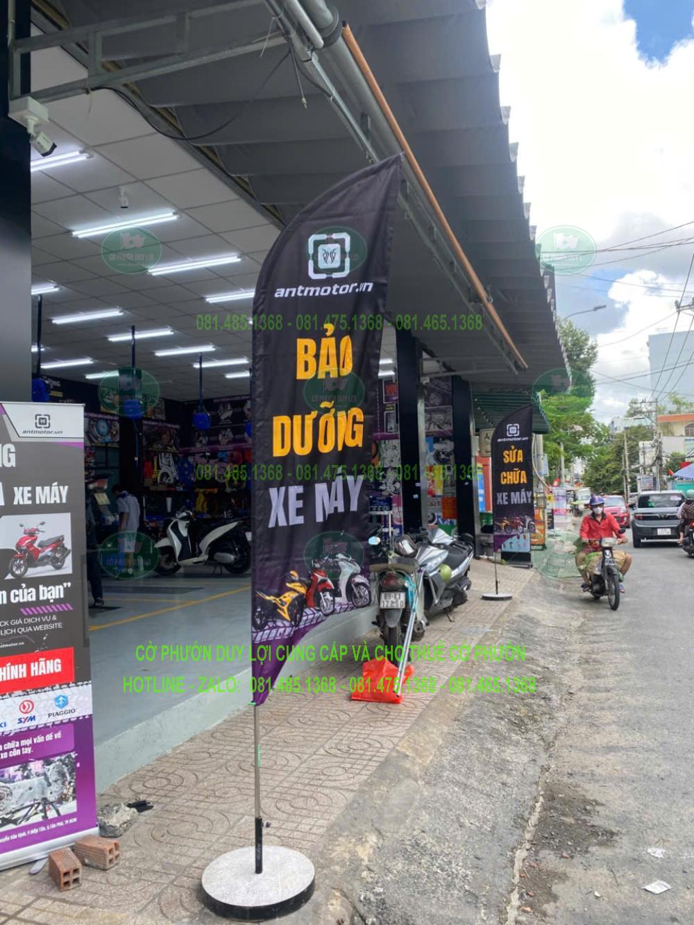 Góc chụp khác của cờ bảo dưỡng xe máy, cho thấy vùng chữ chính và đế tròn tại mặt tiền.