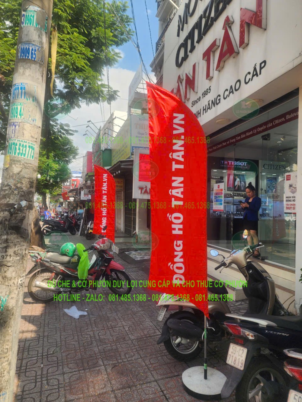 Cờ đỏ mang chữ Đồng hồ Tân Tân, đặt trước cửa hàng cùng các cờ phía sau.