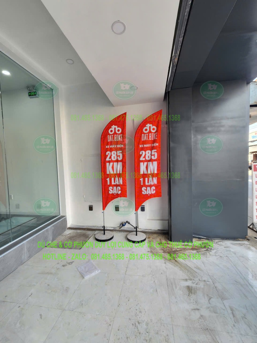 Góc chụp khác của hai cờ đỏ trong nhà, cho thấy vị trí cạnh cửa kính và chân đế rời.
