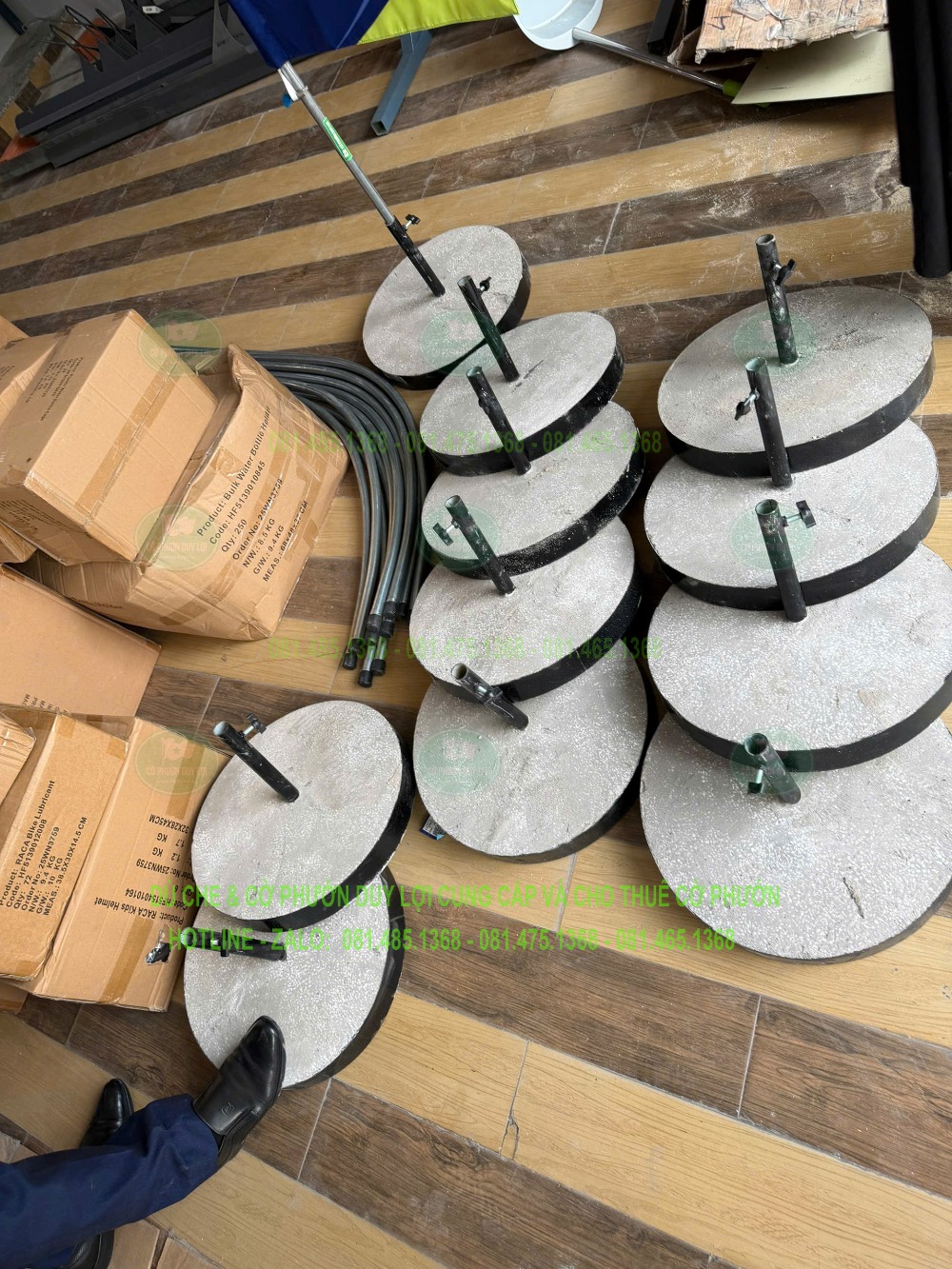 Các đế bê tông dạng tròn có trụ giữ khung được tập kết trên sàn gỗ.